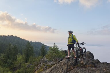 Ein Radfahrer steht mit seinem Mountainbike auf einem Berggipfel. | © Bodenmais Tourismus & Marketing GmbH