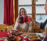 Zwei Frauen stoßen mit Glaskrügen an. Eine der beiden hat Käsespätzle und einen Beilagensalat vor sich stehen, die andere eine Suppe mit zwei Scheiben Bauernbrot | © Bodenmais Tourismus & Marketing GmbH