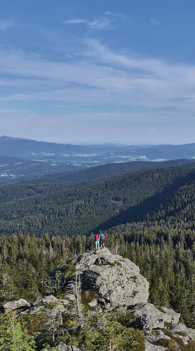 zwei Personen stehe etwas entfernt auf einem Fels und blicken in den Bayerischen Wald. | © Bodenmais Tourismus & Marketing GmbH