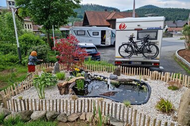 Auf einem Parkplatz hinter einem kleinen, schön angelegtem Teich steht ein Wohnmobil. | © Bodenmais Tourismus & Marketing GmbH
