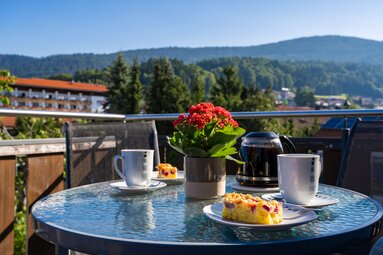 Kaffee und Kuchen steht auf einem Glastisch auf einem Balkon mit Blick auf Bodenmais und ins Grüne | © Bodenmais Tourismus & Marketing GmbH