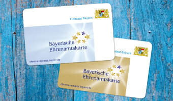 Auf dem Bild sieht man die Ehrenamtskarten im Scheckkartenformat in den Farben gold und silber mit dem Wappen des Freistaat Bayern | © Bayerisches Staatsministerium für Familie, Arbeit und Soziales