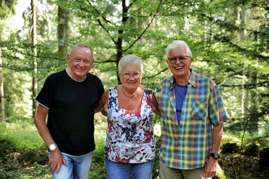 Eine Frau und zwei Männer stehen im Wald  und lachen in die Kamera | © Bodenmais Tourismus & Marketing GmbH