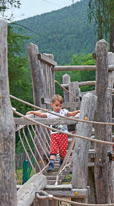 Ein Junge läuft über eine waagerechte, hölzerne Leiter in einem Klettergarten | © Bodenmais Tourismus & Marketing GmbH