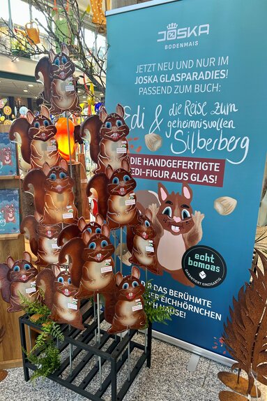 Neben einem Roll-Up mit Infos zum Bodenmaiser Kinderbuch steht eine Vielzahl an gläsernen Eichhörnchen-Figuren | © Bodenmais Tourismus & Marketing GmbH