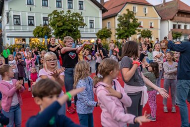Auf dem Marktplatz haben sich Kinder und Betreuer versammelt und tanzen zusammen. | © Bodenmais Tourismus & Marketing GmbH