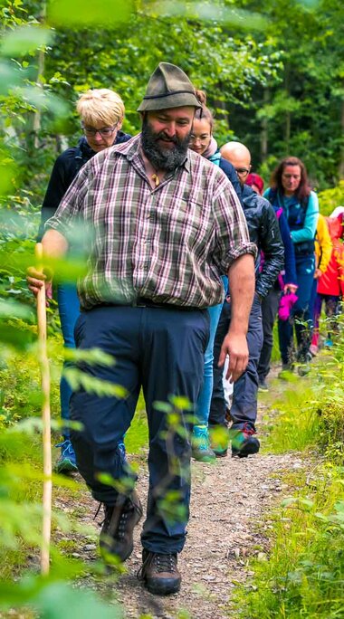 Der Woid Woife geht mit einer Gruppe Erwachsener durch den Wald. | © Bodenmais Tourismus & Marketing GmbH