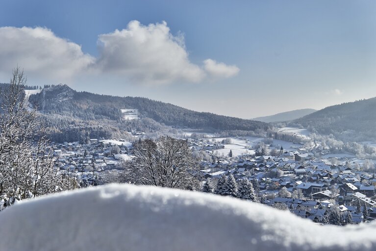 Über einen verschneiten Hügel blickt man hinab auf Bodenmais. Über Bodenmais thront der Silberberg, neben dem auch eine Skipiste zu erkenne ist. | © Bodenmais Tourismus & Marketing GmbH