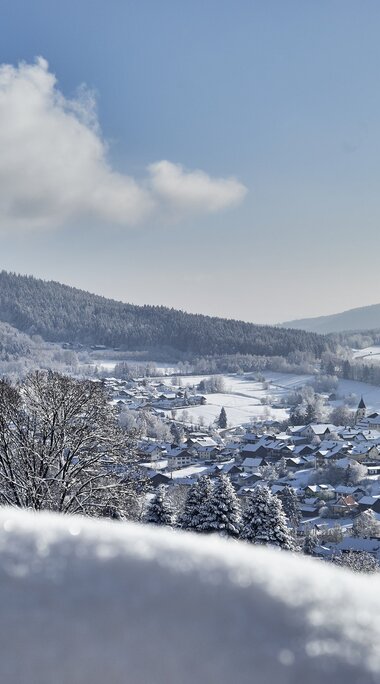 Über einen verschneiten Hügel blickt man hinab auf Bodenmais. Über Bodenmais thront der Silberberg, neben dem auch eine Skipiste zu erkenne ist. | © Bodenmais Tourismus & Marketing GmbH