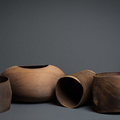 Mehrere Vasen und Gefäße aus dunklem Holz liegen nebeneinander | © Künstler