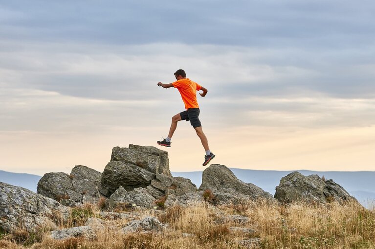 Ein Mann in sportlichem Outfit springt von einem Fels auf den anderen. Er ist mit beiden Füßen in der Luft. | © Bodenmais Tourismus & Marketing GmbH