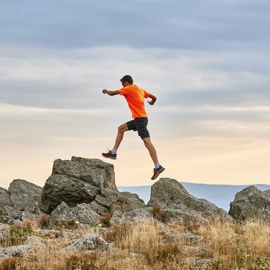 Ein Mann in sportlichem Outfit springt von einem Fels auf den anderen. Er ist mit beiden Füßen in der Luft. | © Bodenmais Tourismus & Marketing GmbH