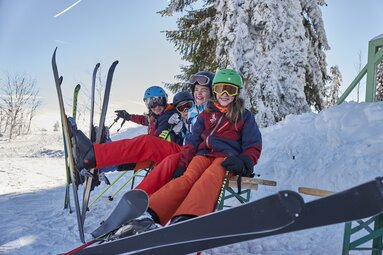Mädchen sitzen lachend mit Skianorak auf Bank auf dem Berg | © Bodenmais Tourismus & Marketing GmbH
