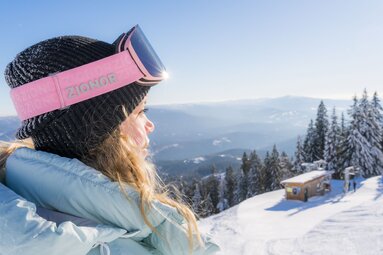 Eine Frau mit dicker Jacke und Skibrille steh auf einer Skipiste. Der Himmel ist strahlend blau. | © Bodenmais Tourismus & Marketing GmbH