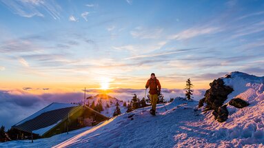 Ein Schneeschuhwanderer befindet sich am Großen Arber. Hinter ihm geht die Sonne unter und im Tal liegt der Nebel. | © Bodenmais Tourismus & Marketing GmbH