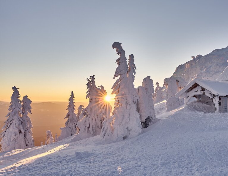 In einer zauberhaften weißen Winterlandschaft steht eine kleine eingeschneite Kapelle. Zwischen weißen Bäumen geht die Sonne unter. | © Bodenmais Tourismus & Marketing GmbH
