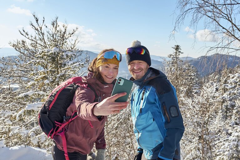 Eine Frau und ein Mann befinden sich mitten in der verschneiten Natur bei prächtigem Wetter. Die Frau macht von sich und ihrem Begleiter ein Selfie. | © Bodenmais Tourismus & Marketing GmbH