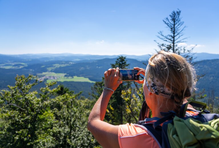 Eine Frau fotografiert beim Wandern den Ausblick mit dem Handy. | © Bodenmais Tourismus & Marketing GmbH