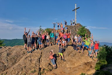 Etliche Teilnehmer in buntem Wanderoutfit stehen auf einem Berggipfel und schmeißen die Hände in die Luft. | © Bodenmais Tourismus & Marketing GmbH