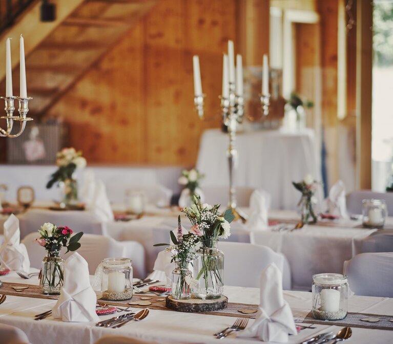 Dekorierte Hochzeitstische mit großen Kerzenständern auf der GutsAlm Harlachberg. | © jokumaxx design