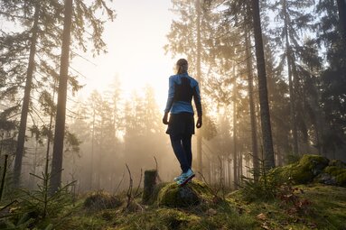Frau steht im Wald und genießt den Sonnenaufgang | © Bodenmais Tourismus & Marketing GmbH