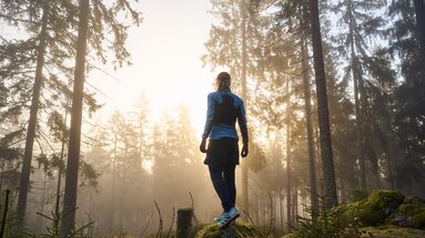 Frau steht im Wald und genießt den Sonnenaufgang | © Bodenmais Tourismus & Marketing GmbH