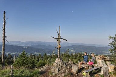Ein Paar sitzt auf einer Bank am Gipfel des Heugstatt. | © Bodenmais Tourismus & Marketing GmbH