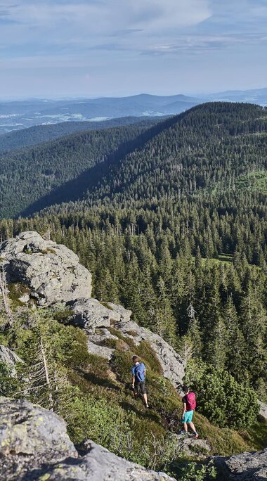 Zwei Wanderer laufen zum Gipfel des Großen Arber und haben dabei eine fantastische Aussicht auf den Bayerischen Wald. | © Bodenmais Tourismus & Marketing GmbH