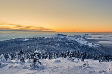 Vom Gipfel des Großen Arber blickt man auf den verschneiten Bayerischen Wald, über dem die Sonne untergeht. | © Bodenmais Tourismus & Marketing GmbH