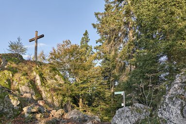 Auf einem Fels im Wald steht ein Gipfelkreuz. | © Bodenmais Tourismus & Marketing GmbH