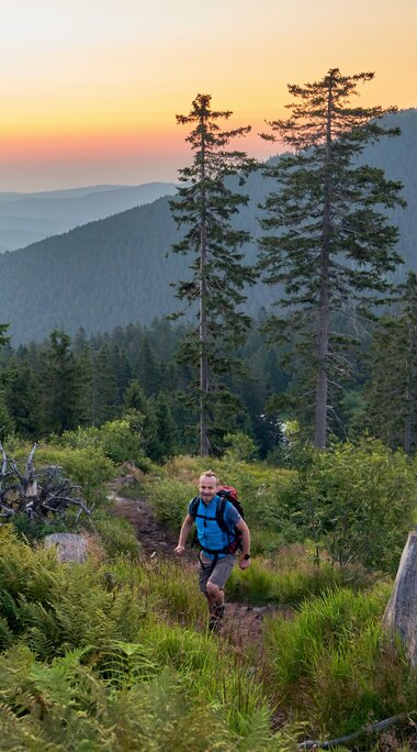 Ein Wanderer geht bei Sonnenaufgang auf den Kleinen Arber. Im Hintergrund sieht man den Großen Arber | © Bodenmais Tourismus & Marketing GmbH