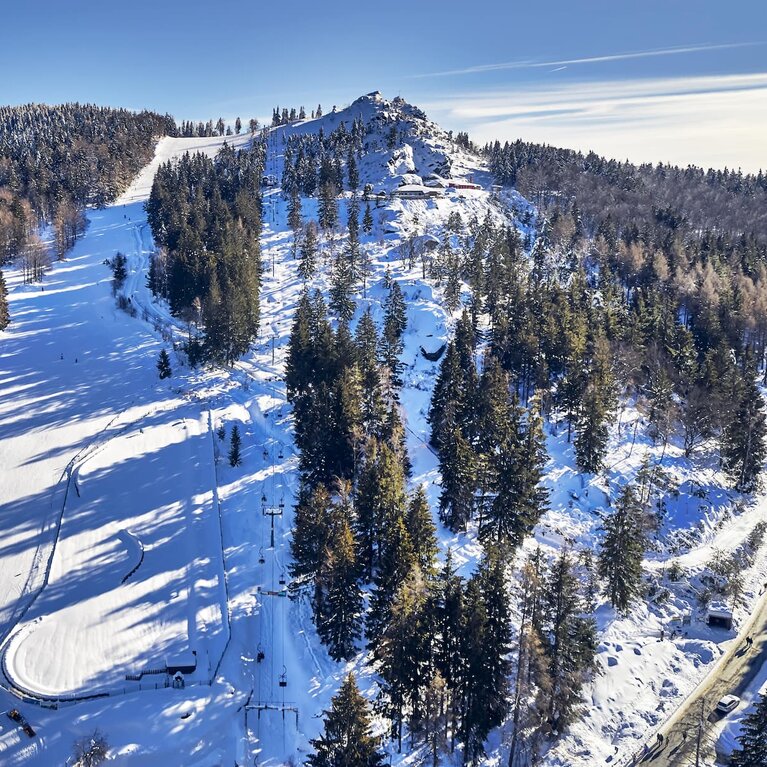 An einem sonnigen Wintertag blickt man aus der Vogelperspektive auf die Skipiste und den Gipfel des Silberbergs. | © Bodenmais Tourismus & Marketing GmbH