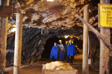 Eine Besuchergruppe mit blauen Kitteln und gelben Helmen läuft durch den Stollen des Bergwerks im Silberberg. | © Bodenmais Tourismus & Marketing GmbH