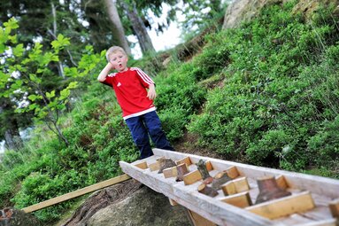 Ein Junge steht im Wald vor einem Spielzeug aus Holz. | © Bodenmais Tourismus & Marketing GmbH