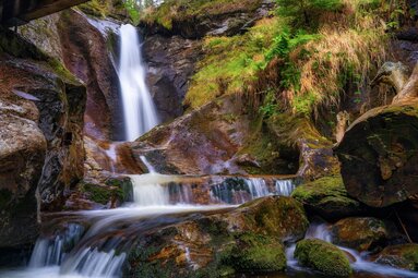 Ein Wasserfall fällt glatt gespülten Fels hinab. Daneben ist der Stein mit Moos bewachsen. | © Bodenmais Tourismus & Marketing GmbH