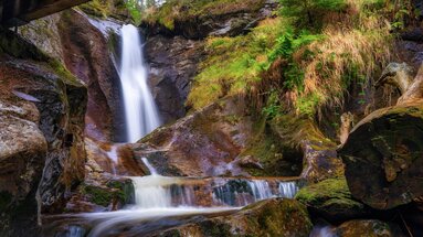Ein Wasserfall fällt glatt gespülten Fels hinab. Daneben ist der Stein mit Moos bewachsen. | © Bodenmais Tourismus & Marketing GmbH