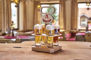 Auf einem Tisch steht ein Holztragerl mit vier gefüllten Biergläsern darin. | © Bodenmais Tourismus & Marketing GmbH